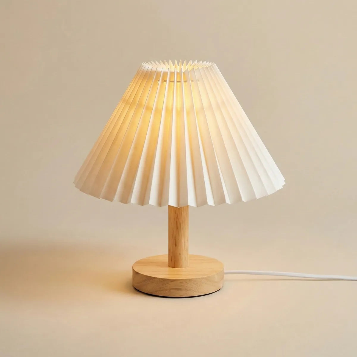 Abajur de mesa minimalista estilo Japandi com base de madeira clara e cúpula plissada isolado em fundo neutro.