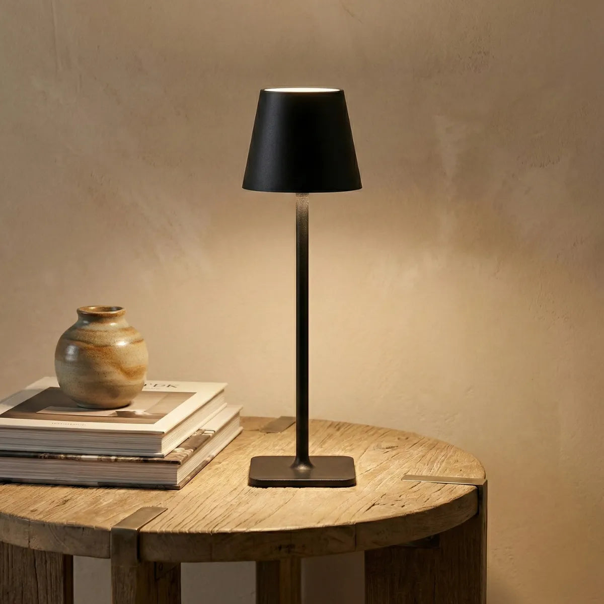 Abajur de mesa Slim preto iluminando escrivaninha de madeira com decoração sóbria em home office moderno.