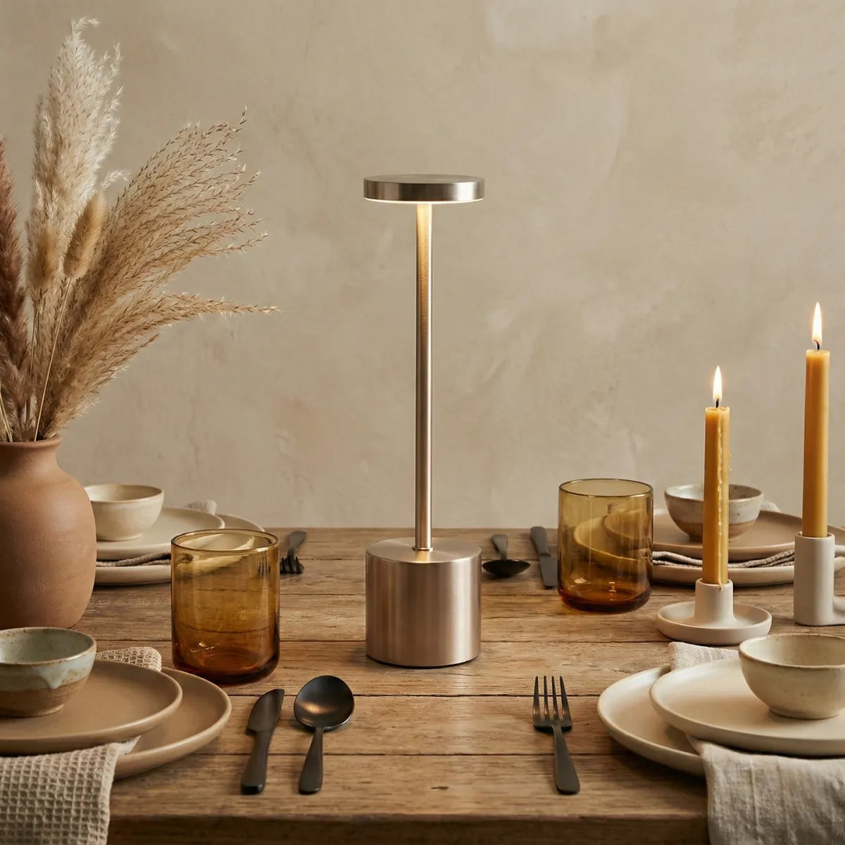 Luminária de mesa Allure Champagne compondo decoração de mesa posta elegante com velas, copos de vidro âmbar e flores secas.