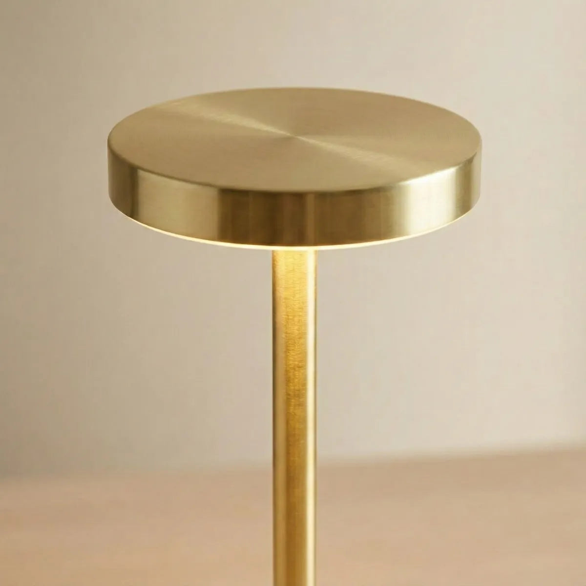 Close-up do topo da luminária Allure Dourada, mostrando o acabamento em metal escovado e a luz LED suave.