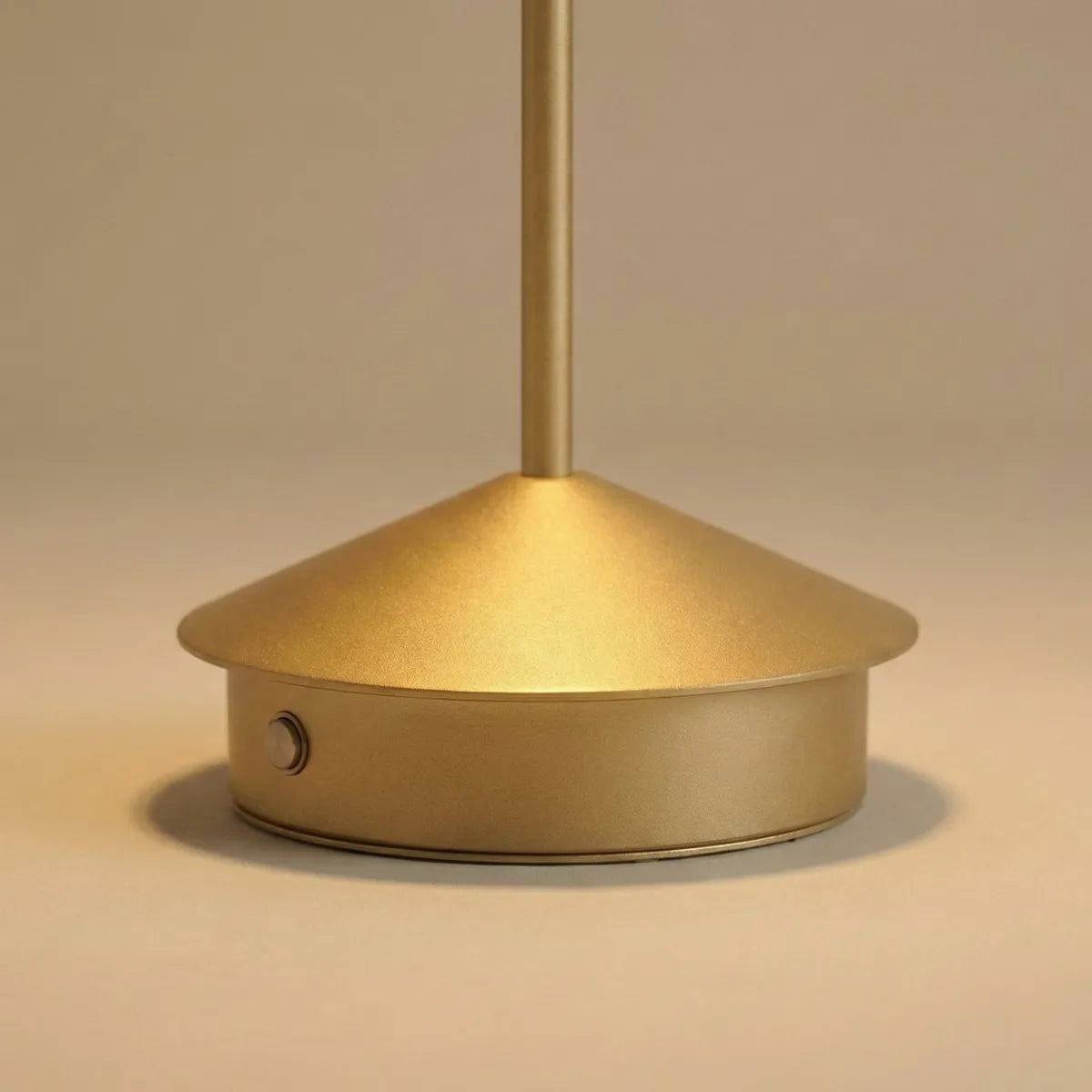 Detalhe da base cônica e acabamento da luminária de mesa Apollo dourada com foco na textura metalizada fosca e botão de toque.