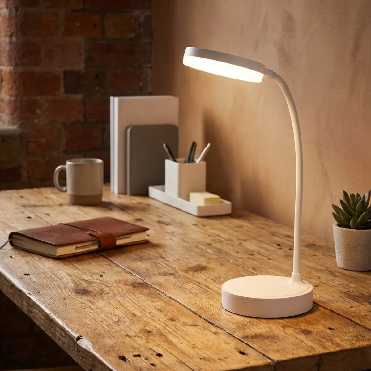 Luminária de mesa articulável branca iluminando escrivaninha de madeira rústica em home office estilo industrial com parede de tijolos aparentes.