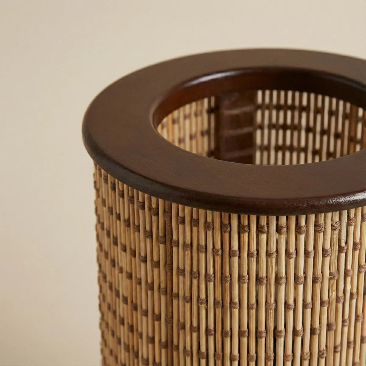 Close no acabamento superior da luminária Senda mostrando a textura do bambu trançado e o anel de madeira escura.