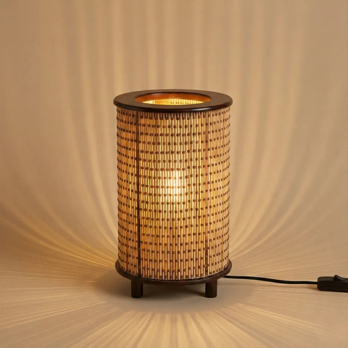 Luminária de mesa Senda acesa projetando efeito de luz e sombra estriado na parede, criando atmosfera relaxante.