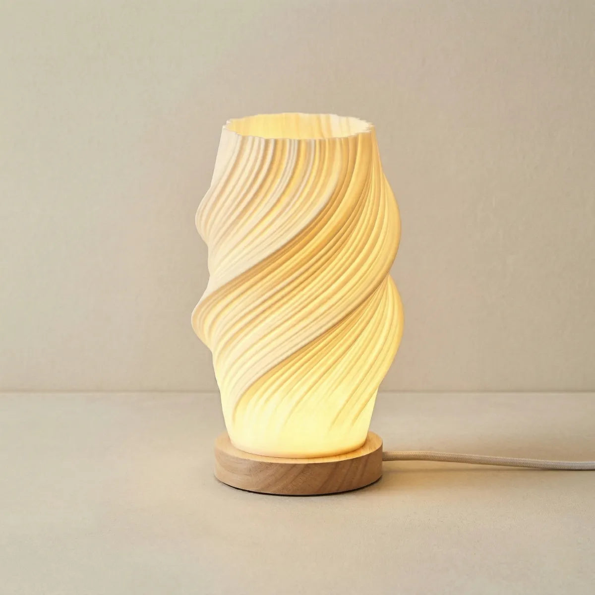 Luminária de mesa com base de madeira e cúpula branca com textura canelada vertical e bordas onduladas. Está sobre um tecido de linho claro com fundo liso e bege.