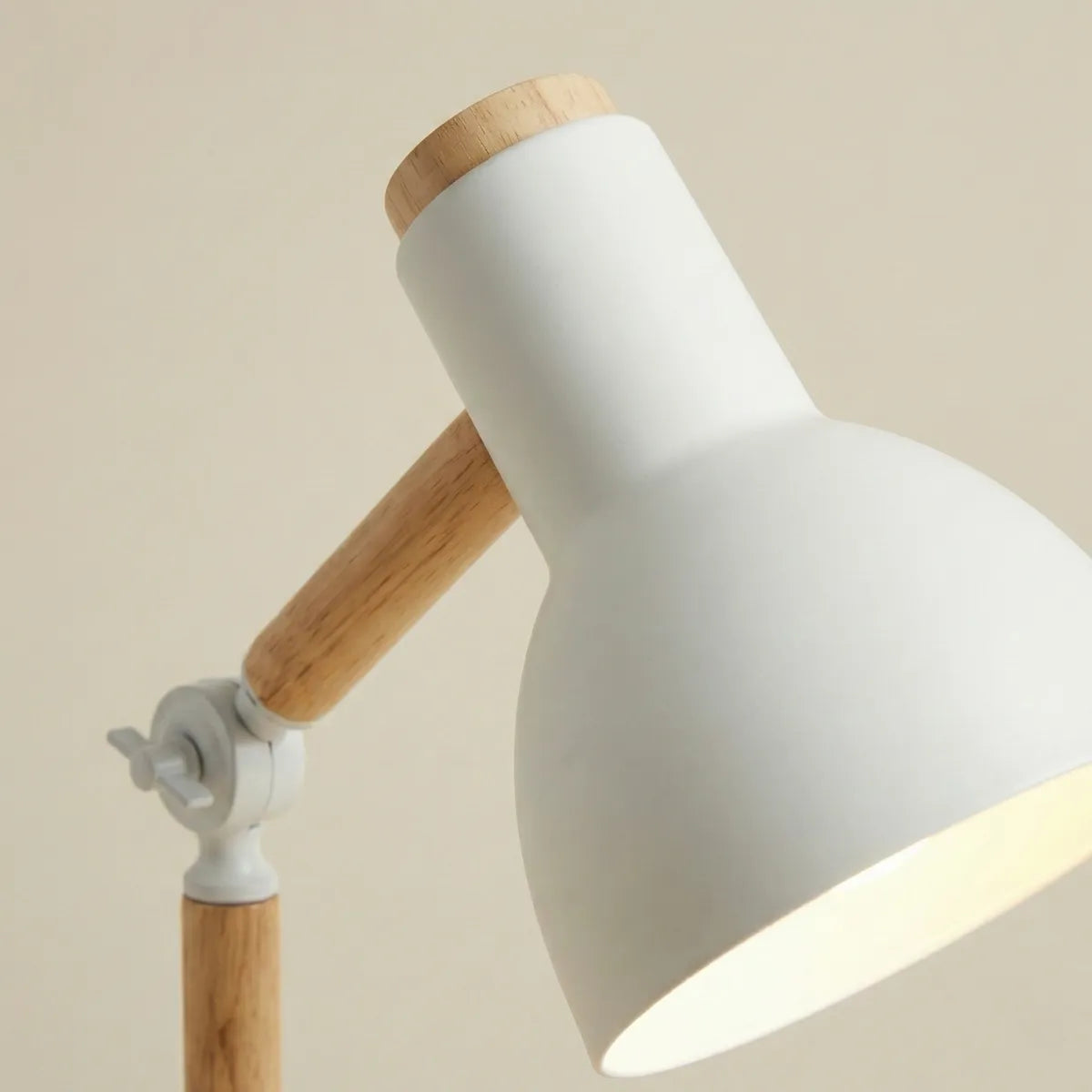 Detalhe da cúpula branca fosca e do acabamento em madeira do braço articulável da luminária de mesa Pinus.