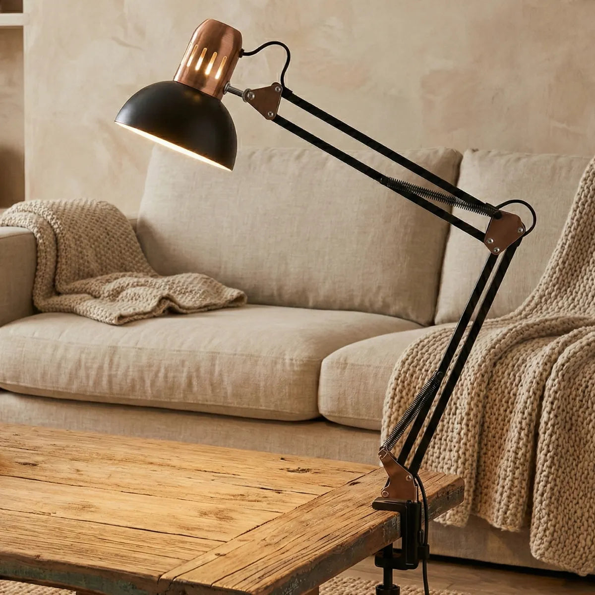 Luminária articulada de estilo industrial presa à mesa de centro na sala de estar, criando contraste moderno com sofá de linho bege e mantas de tricô.