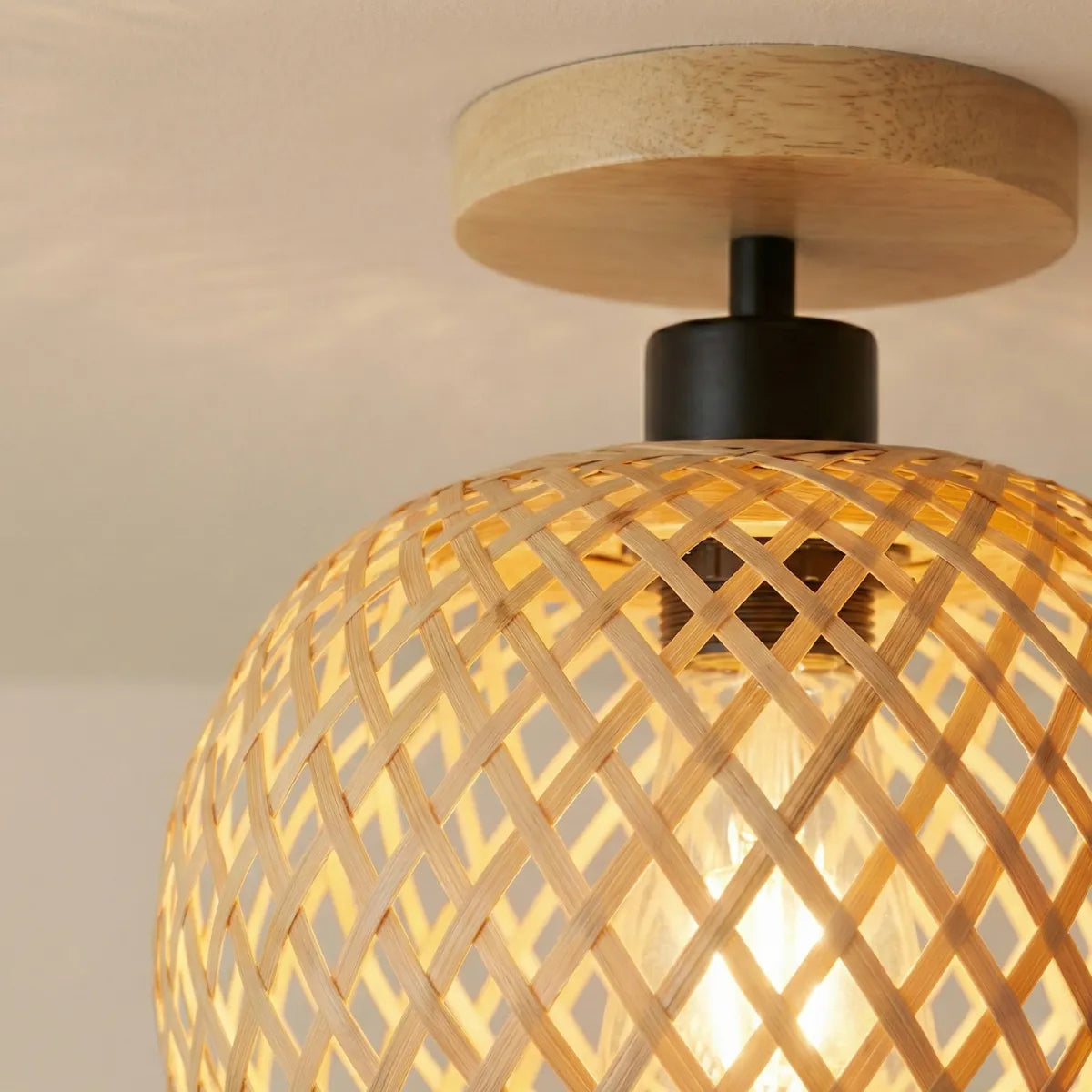 Detalhe da trama de bambu entrelaçada da luminária de teto Fibrato com vista para a lâmpada interna e acabamento superior em madeira.