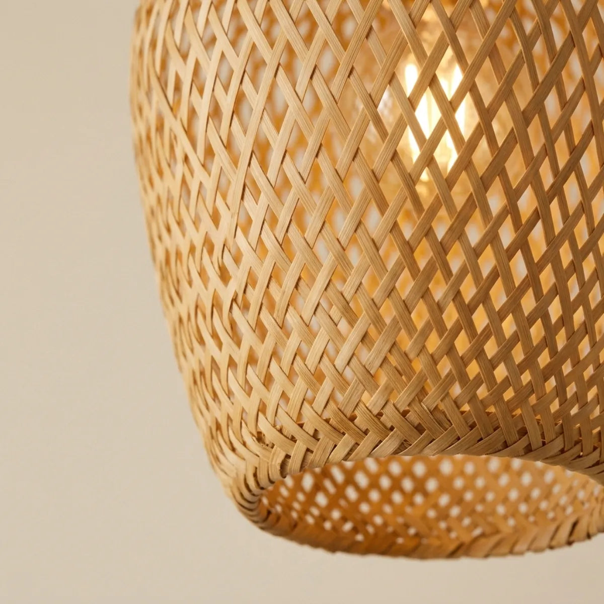 Detalhe em close da textura da Luminária Pendente Bambu Ânfora. O entrelace artesanal da fibra natural filtra a luz quente da lâmpada, evidenciando a qualidade do acabamento.