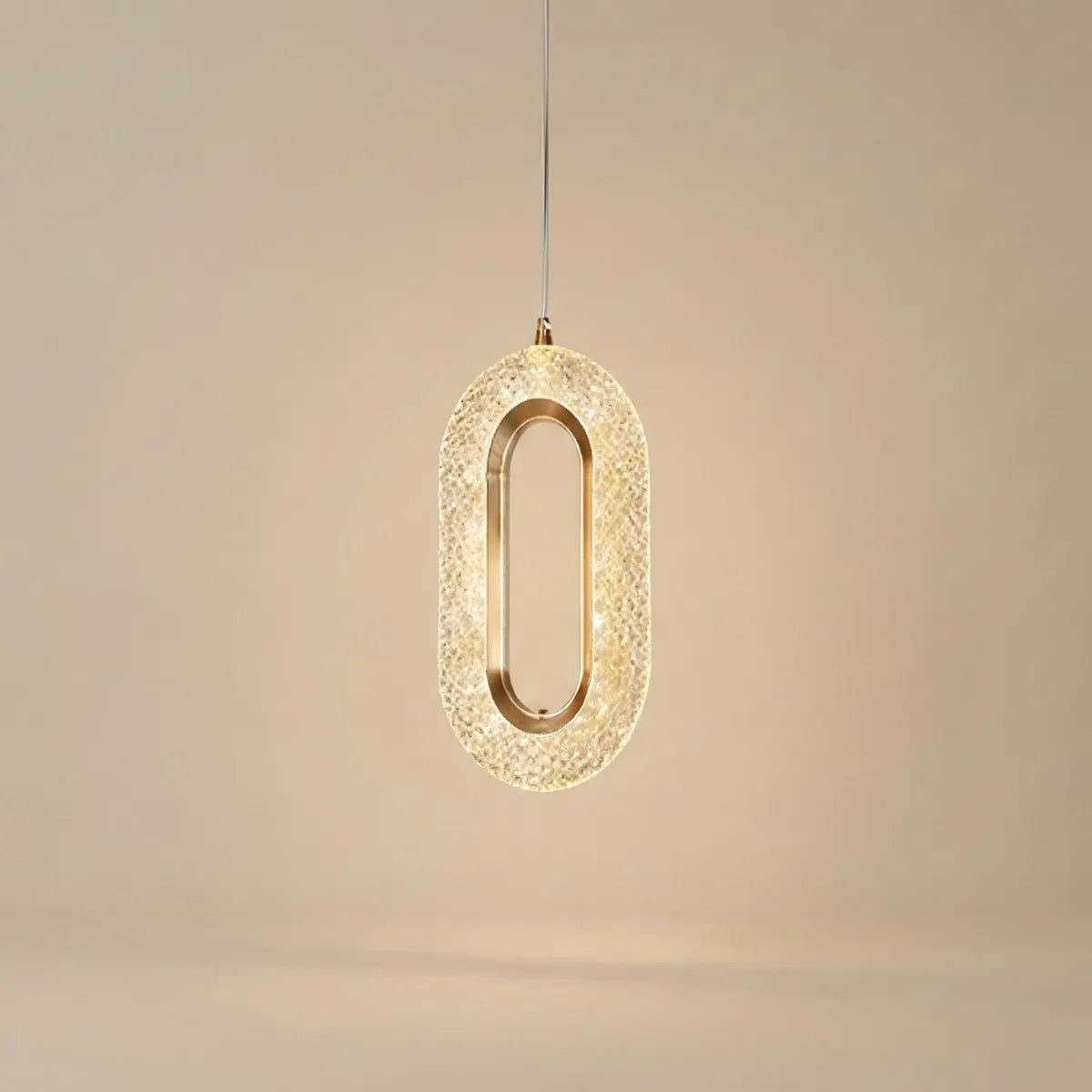 Luminária de teto pendente oval de cristal com acabamento dourado e design de luxo isolada em fundo neutro.
