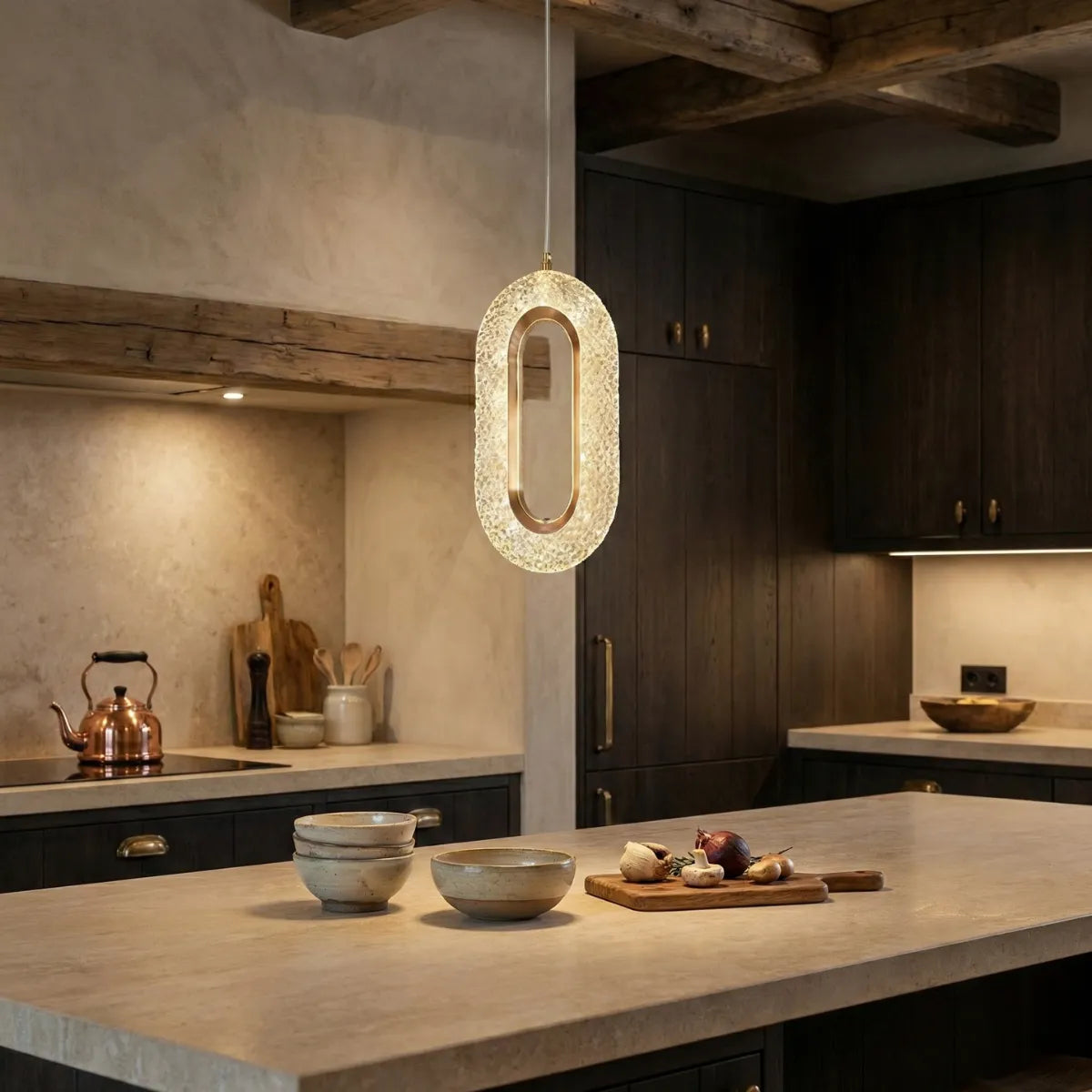 Luminária pendente de cristal sobre ilha de cozinha sofisticada com armários em madeira escura e bancada de pedra.