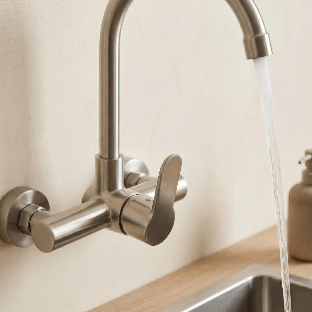 Detalhe da alavanca monocomando da torneira de parede inox escovado com água correndo