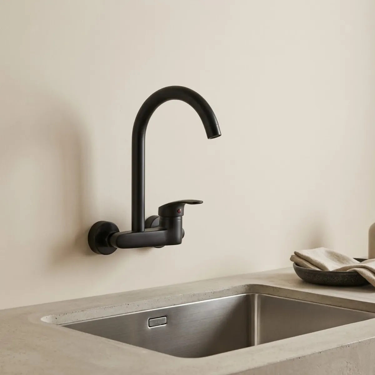 Torneira para cozinha de parede gourmet preta matte com bica alta sobre pia de inox em ambiente minimalista de fundo neutro