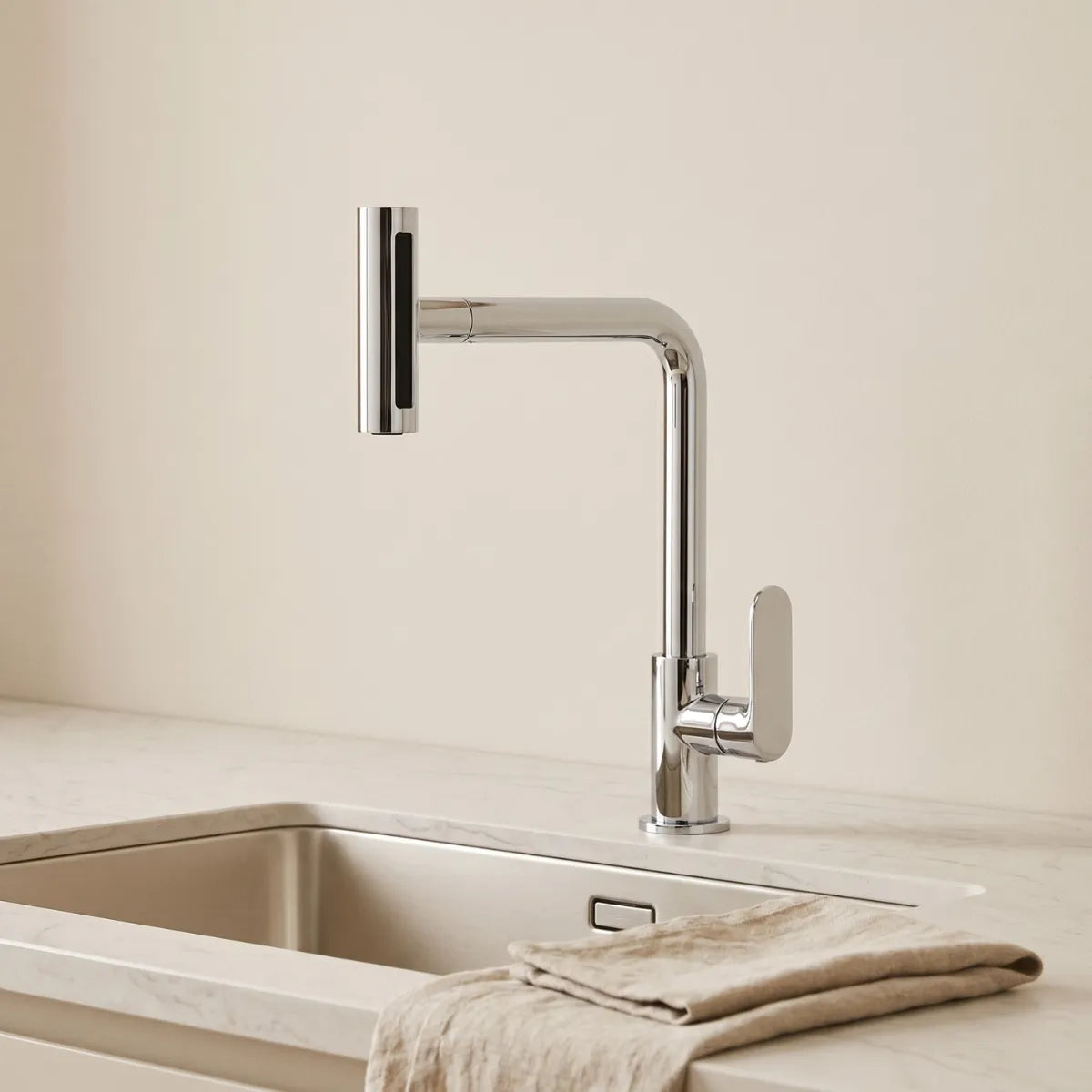 Torneira para cozinha gourmet cromada Pivot 4 em 1 com bica angular e bocal rotativo recolhido, instalada em bancada de mármore branco com cuba de inox e pano de linho.