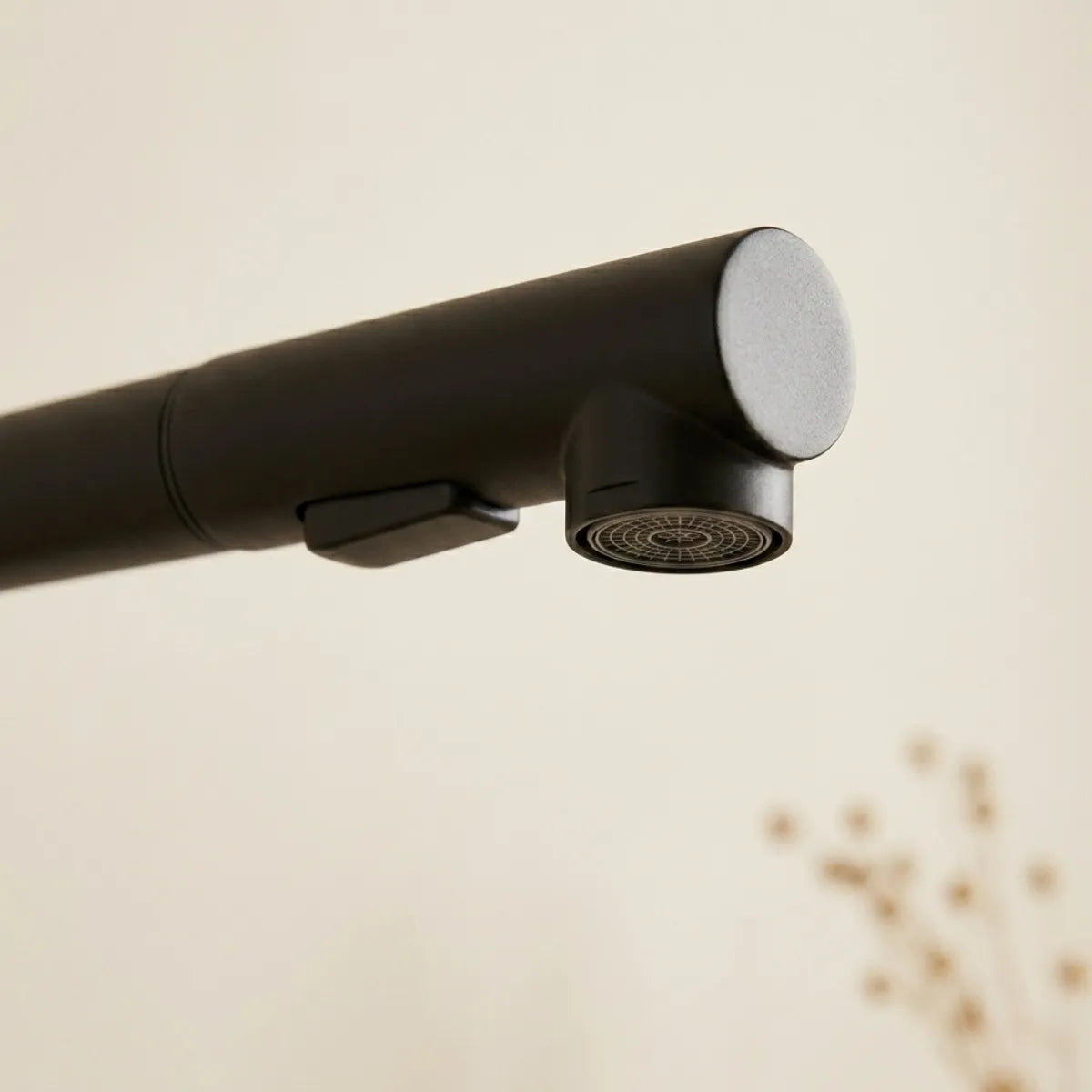 Detalhe do bocal da torneira para cozinha monocomando preta Noir, com aerador circular e botão seletor de jato em acabamento matte, fundo neutro desfocado.
