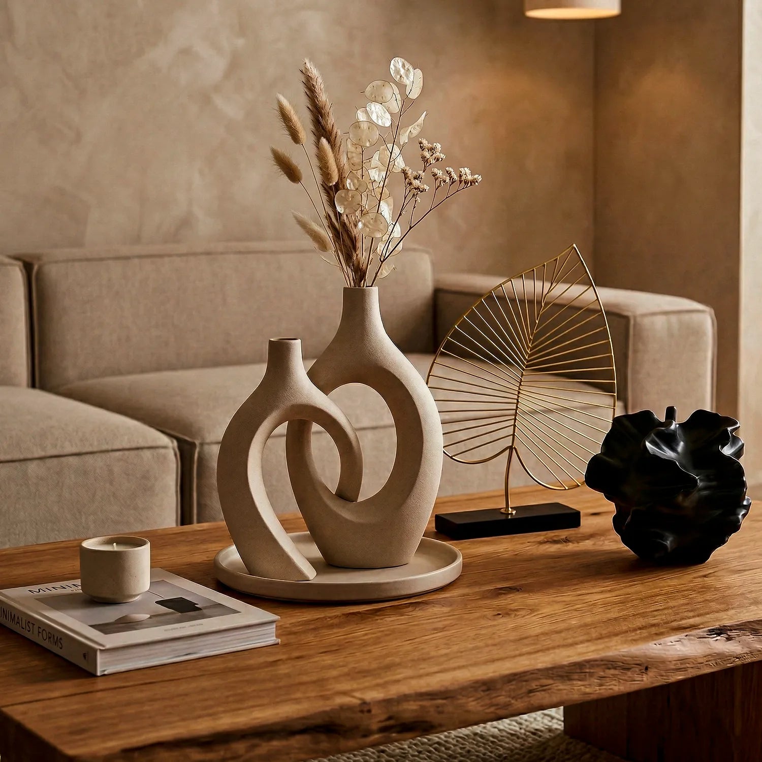 Sala de estar sofisticada em tons quentes. Foque na mesa de centro rústica com vasos cerâmicos orgânicos bege entrelaçados, flores secas, escultura de folha em arame dourado, objeto preto abstrato e iluminação suave.
