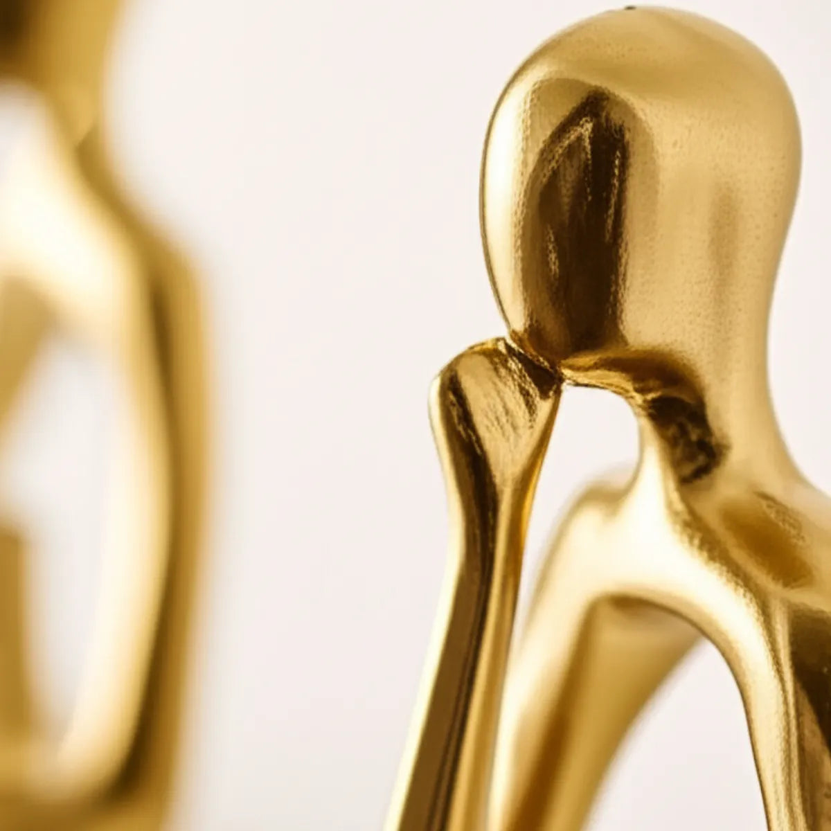 escultura-decorativa-trio-abstrato-dourado-modernize-foto-detalhe-lateral-trio-de-estatuas-douradas-em-fundo-bege