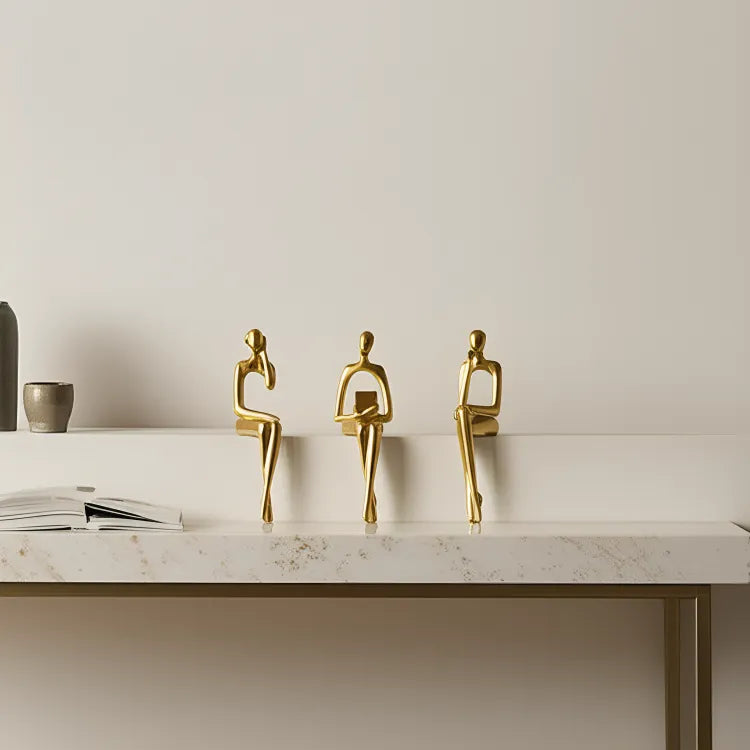 escultura-decorativa-trio-abstrato-dourado-modernize-foto-trio-de-estatuas-douradas-em-mesa-branca