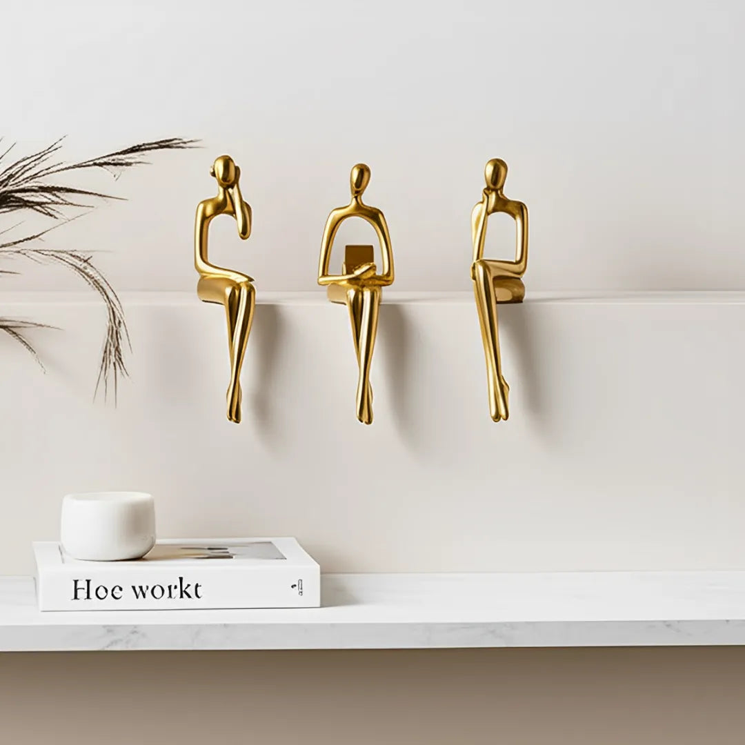 escultura-decorativa-trio-abstrato-dourado-modernize-foto-trio-de-estatuas-douradas-em-parede-branca-fundo-bege