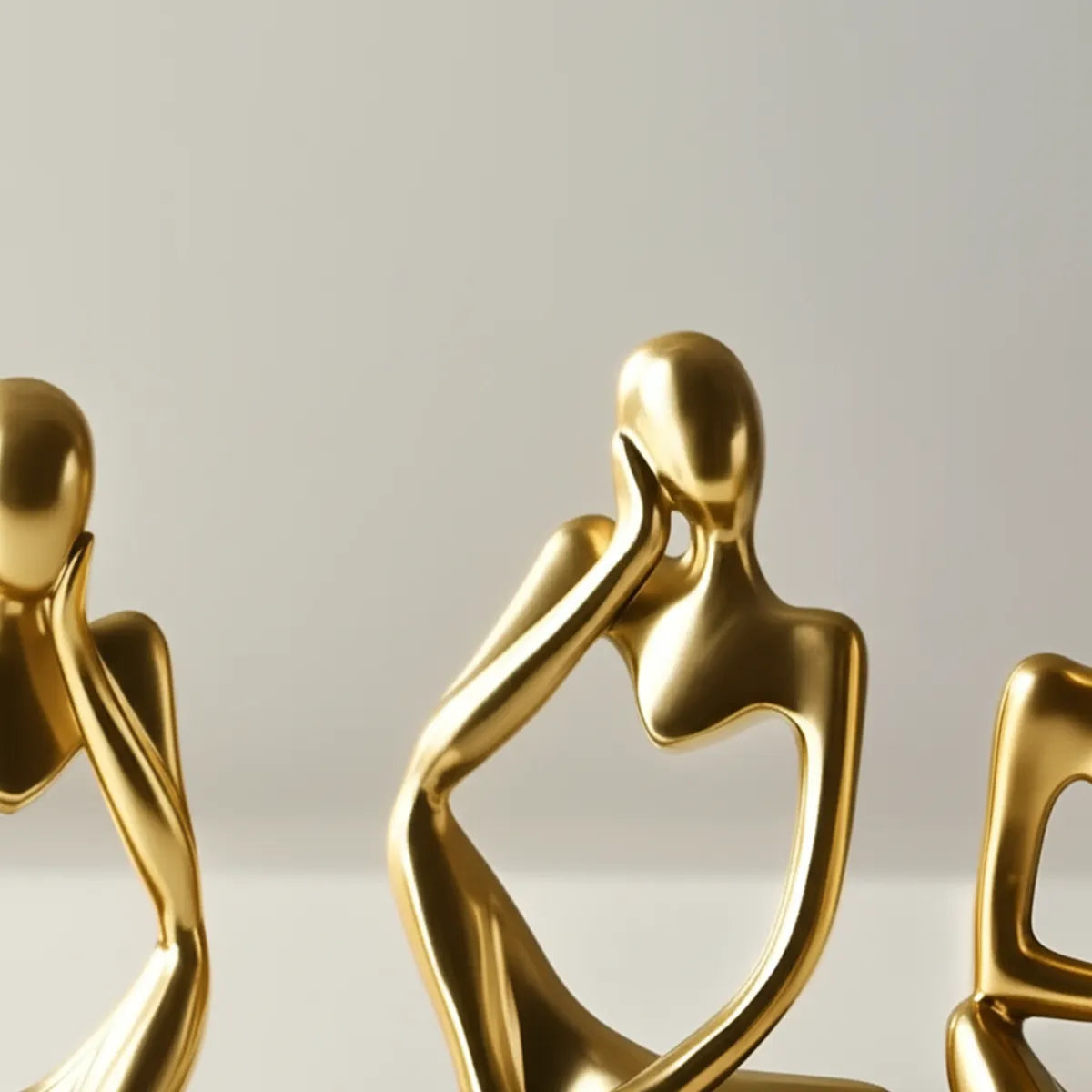 escultura-decorativa-trio-pensador-dourado-modernize-foto-detalhe-textura-esculturas-em-ambiente-claro-fundo-bege