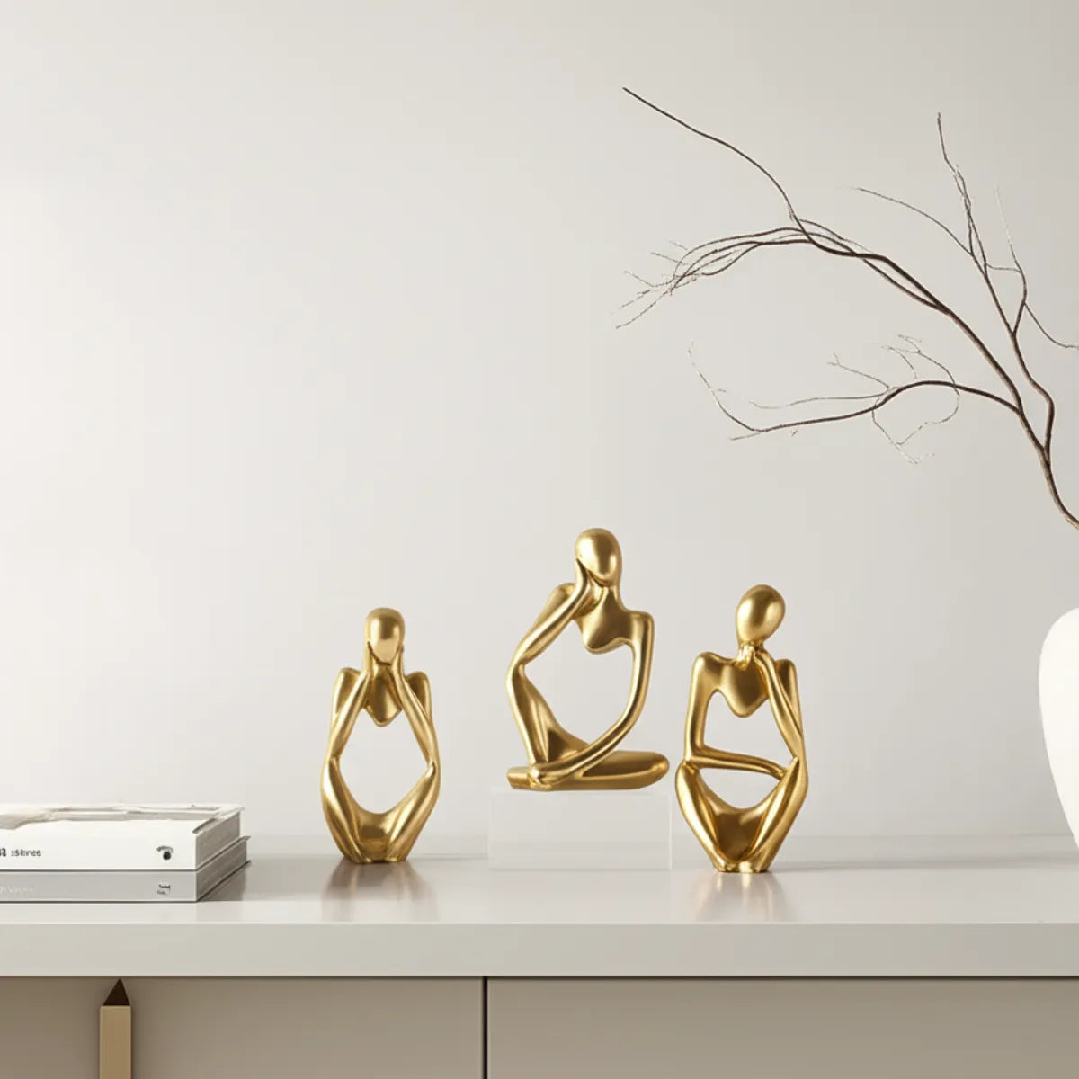 escultura-decorativa-trio-pensador-dourado-modernize-foto-esculturas-em-balcao-ambiente-claro-tons-beges
