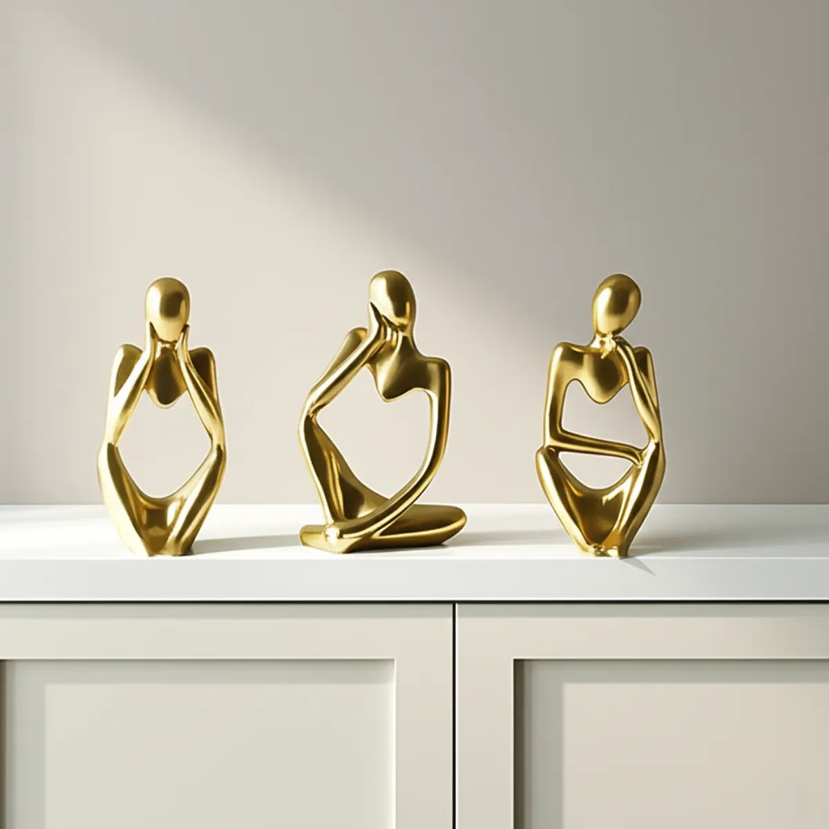 escultura-decorativa-trio-pensador-dourado-modernize-foto-esculturas-em-armario-ambiente-claro-tons-beges