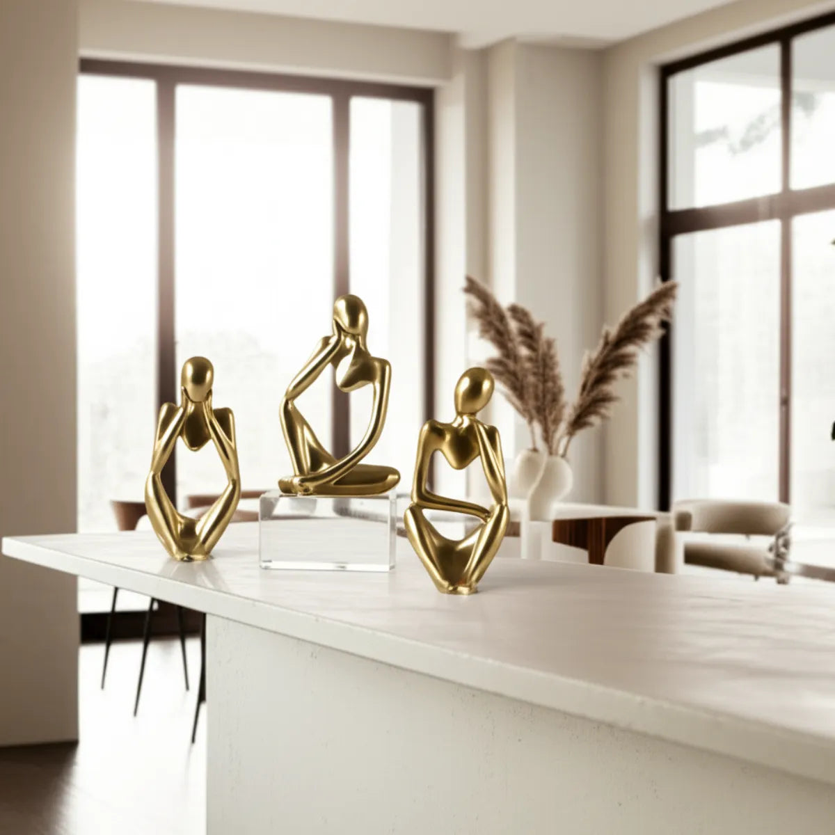 escultura-decorativa-trio-pensador-dourado-modernize-foto-esculturas-em-balcao-ambiente-claro-arejado-tons-beges