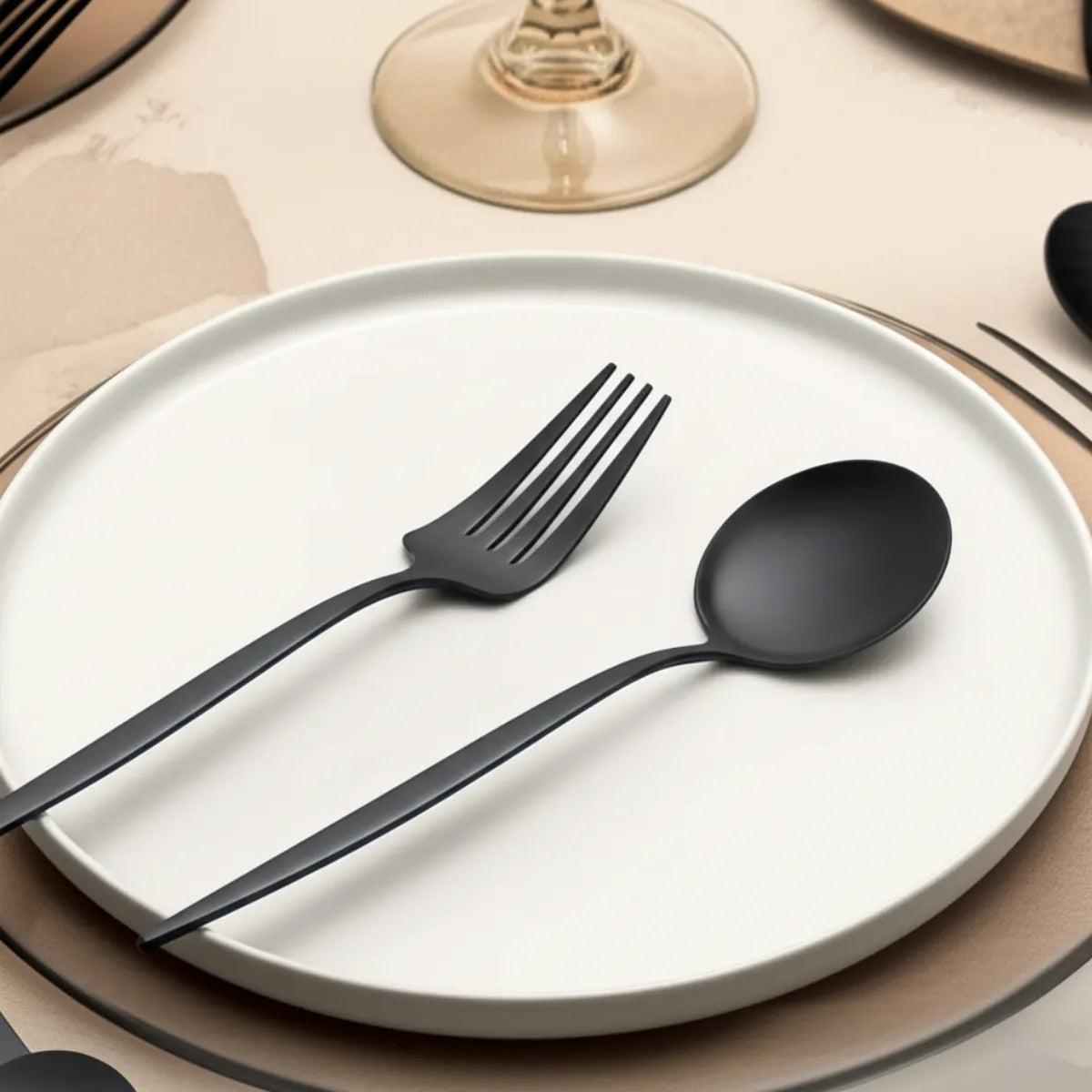 jogo-de-talheres-em-inox-elegance-preto-30-pecas-modernize-foto-garfo-e-colher-em-prato-branco-mesa-moderna-ambiente-claro