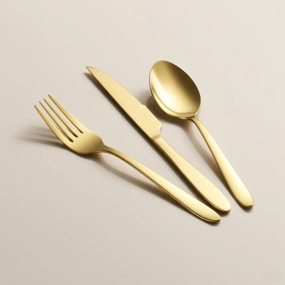 jogo-de-talheres-em-inox-golden-dourado-24-pecas-modernize-foto-talheres-dourados-em-fundo-bege