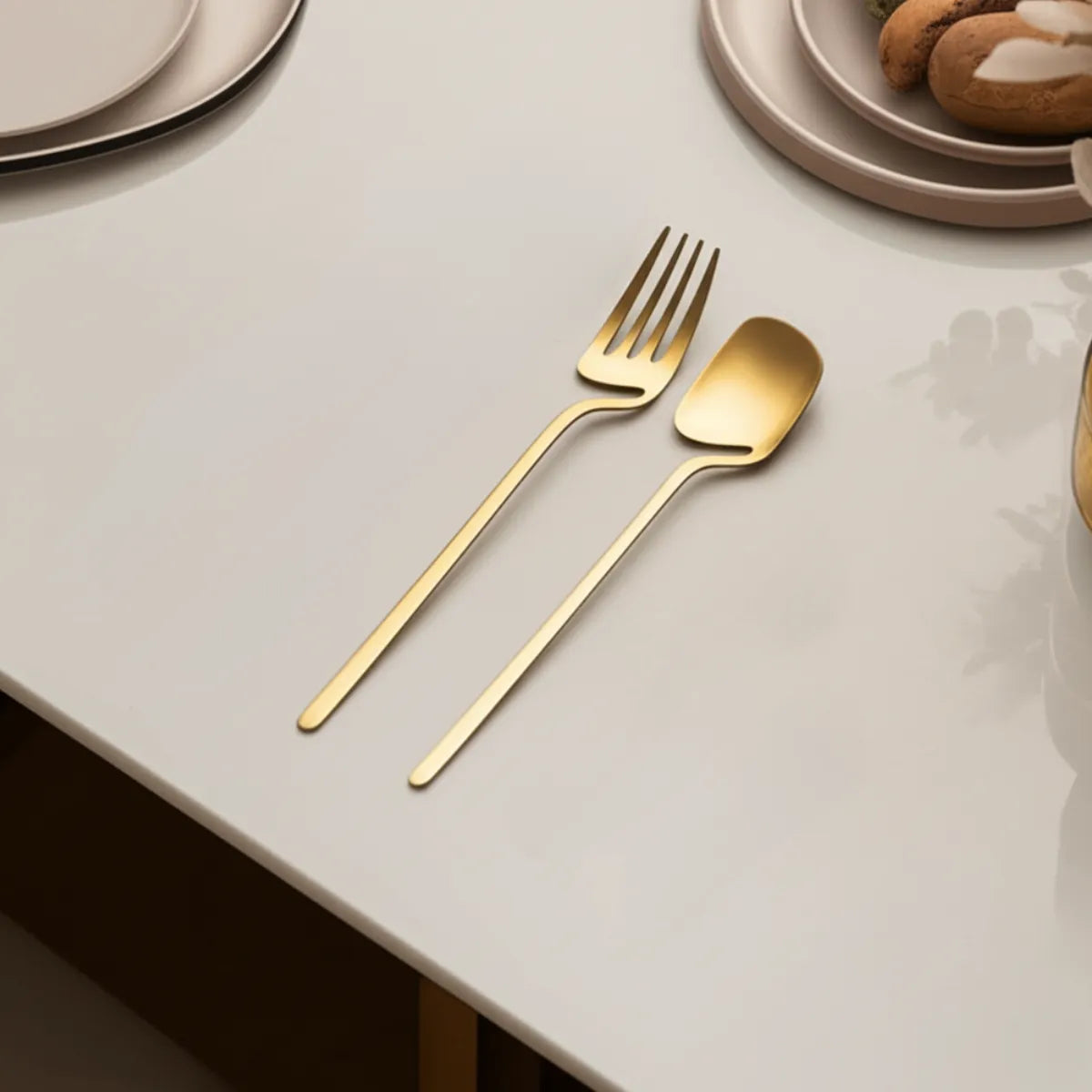 jogo-de-talheres-em-inox-linha-luxo-dourado-32-pecas-modernize-foto-talheres-em-mesa-moderna-branca-ambiente-claro
