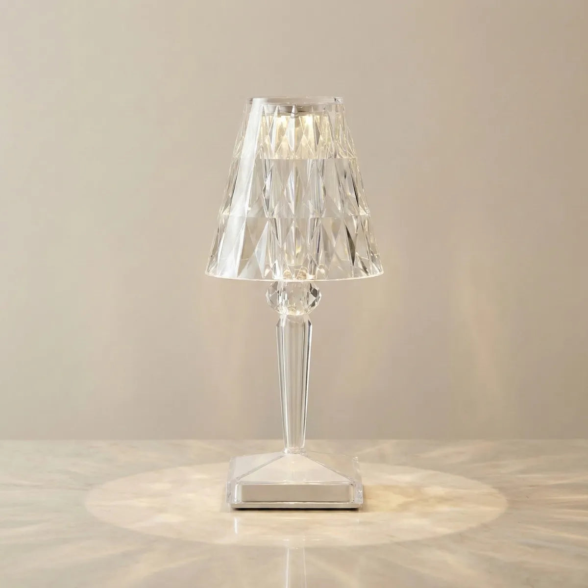 Abajur de mesa Cristal aceso em fundo neutro, demonstrando o efeito radial de luz que a peça projeta sobre a superfície de apoio.