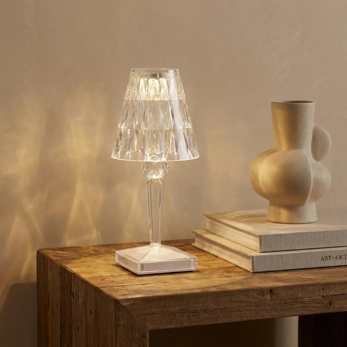 Abajur de mesa transparente sobre aparador de madeira, projetando padrões geométricos de luz e sombra na parede, estilo "light design" minimalista.