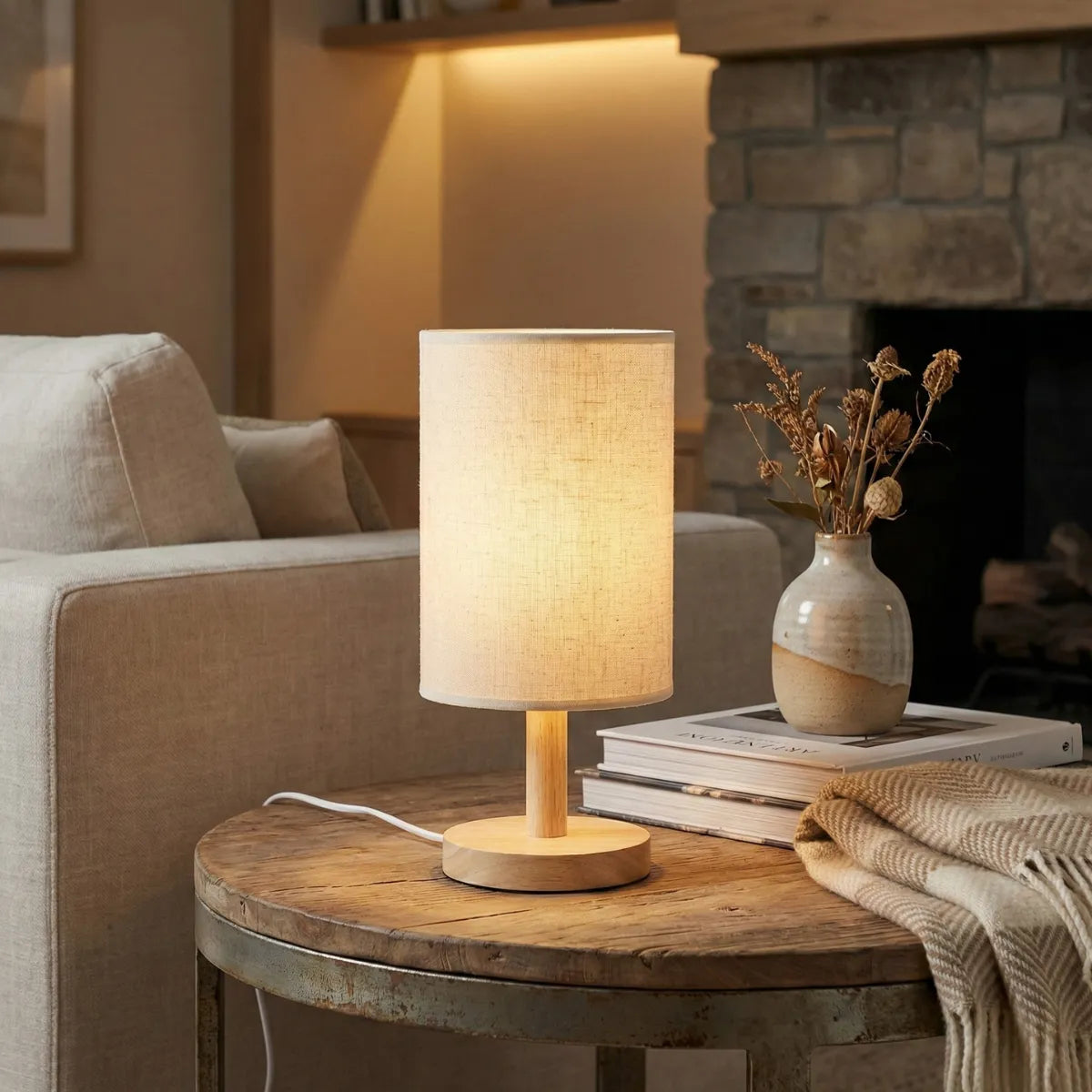 Abajur de mesa Fuste decorando mesa de centro de madeira rústica em sala de estar aconchegante com lareira de pedra ao fundo.