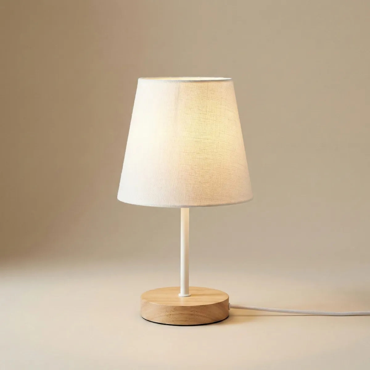 Abajur de mesa minimalista estilo retrô com cúpula de tecido branco e base de madeira clara isolado em fundo neutro.