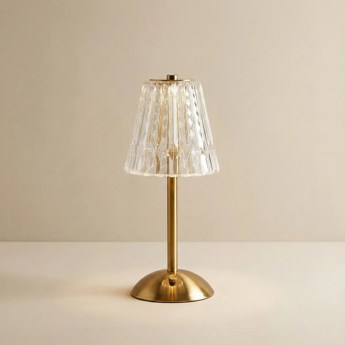 Abajur de Mesa Selene com base em metal dourado escovado e cúpula de cristal acrílico facetado, design moderno e luxuoso.