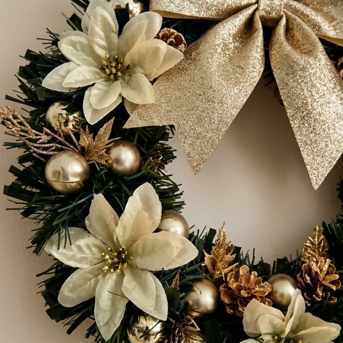 Detalhe da guirlanda com flores brancas e laço dourado glitter, pinhas e esferas em close