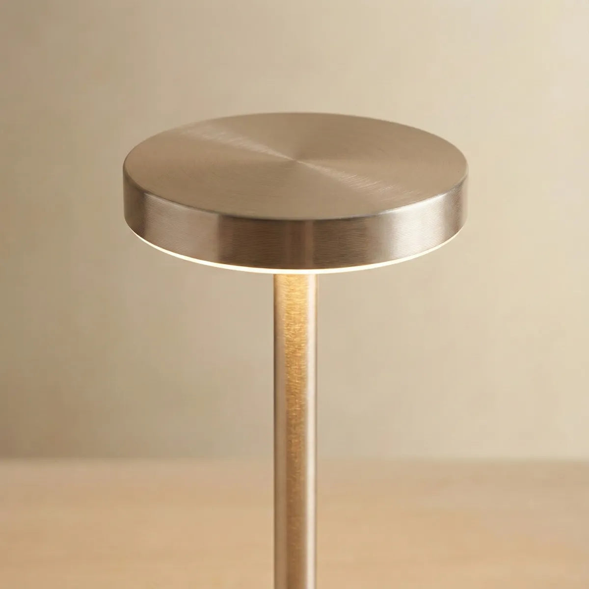 Detalhe do acabamento metálico acetinado da luminária de mesa Allure Champagne destacando o design minimalista e luz LED confortável.