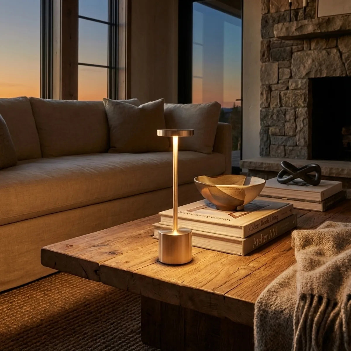 Luminária de mesa sem fio Allure Champagne iluminando mesa de centro de madeira em sala de estar moderna com lareira ao entardecer.