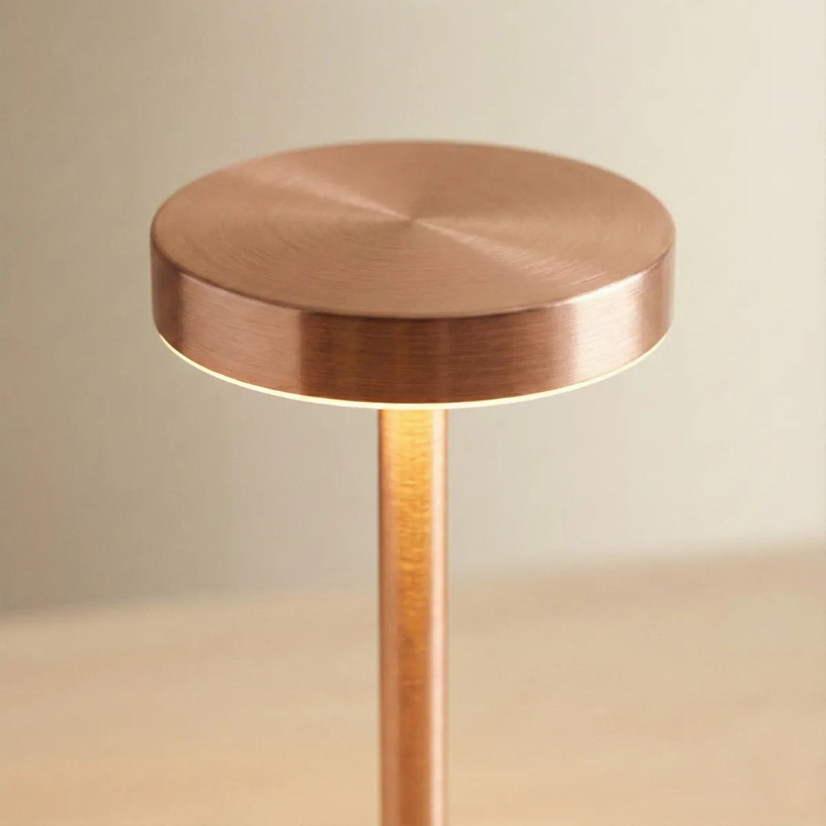 Close-up do topo da luminária Allure Rose Gold, destacando a textura premium de metal escovado e a iluminação LED indireta.