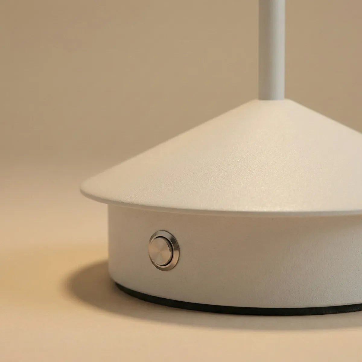 Detalhe da base minimalista da luminária de mesa Apollo branca com foco no acabamento fosco premium e botão de toque.