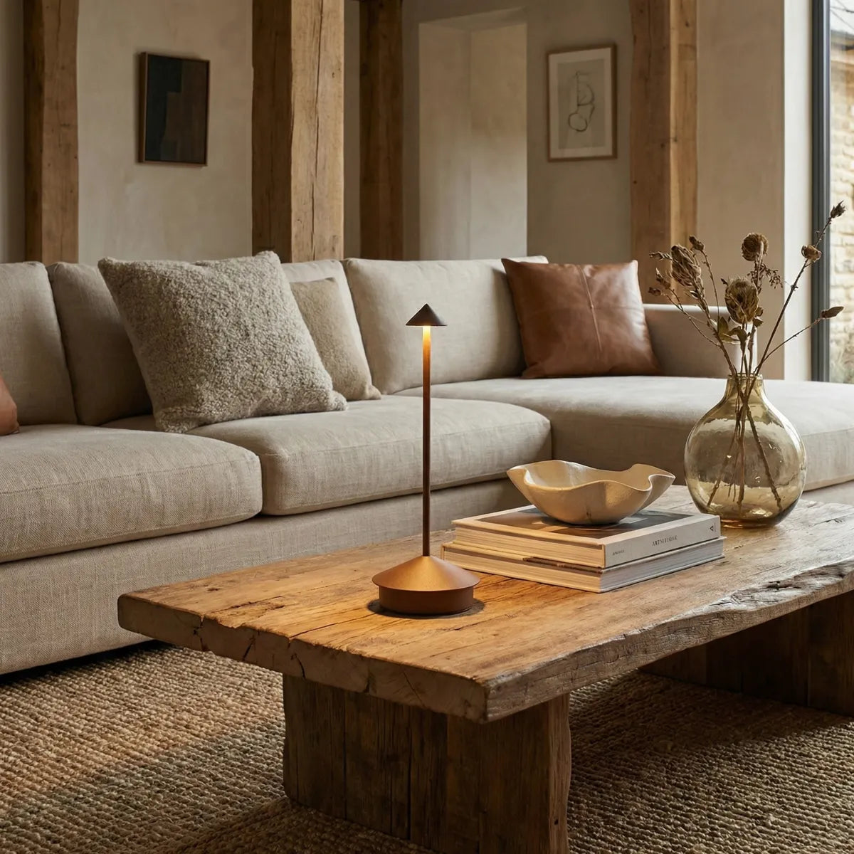 Luminária de mesa portátil Apollo marrom compondo decoração de sala de estar moderna com sofá bege e mesa de tronco natural.