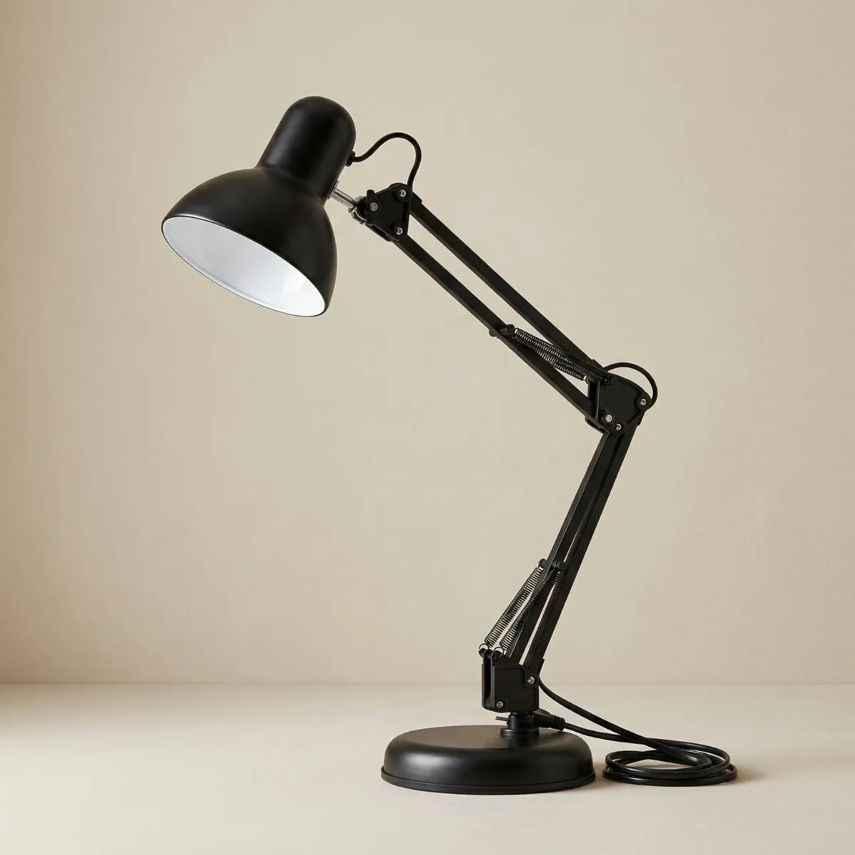 Foto de estúdio da Luminária de Mesa Artic Preta, com base cúbica e braço articulado com juntas visíveis e mola, contra um fundo bege neutro.