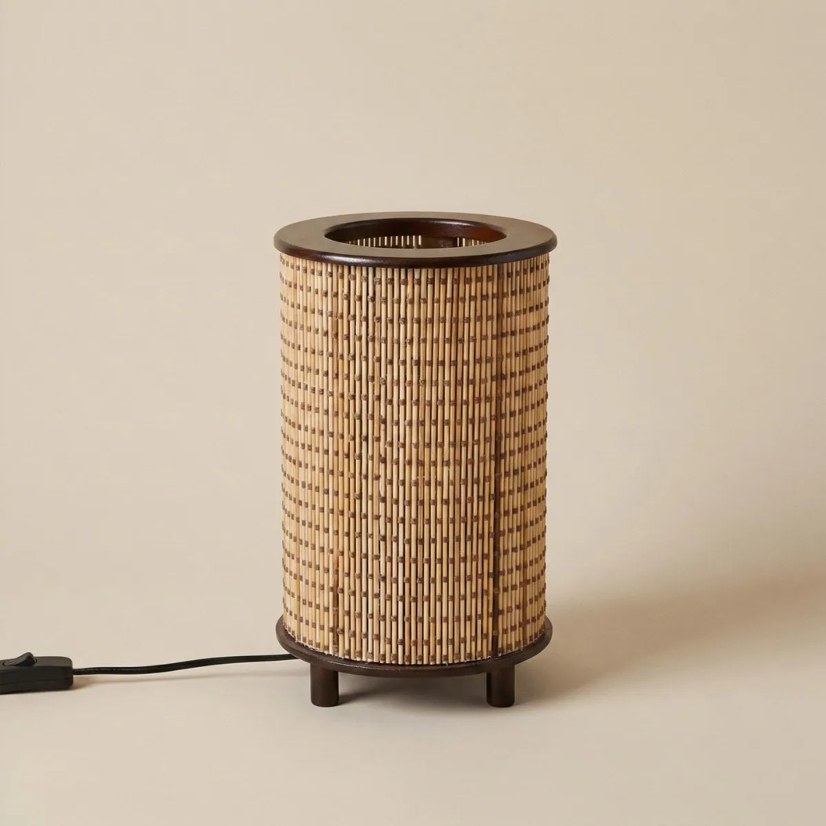 Luminária de mesa Senda cilíndrica feita em bambu natural, estilo boho chic, isolada em fundo bege claro.