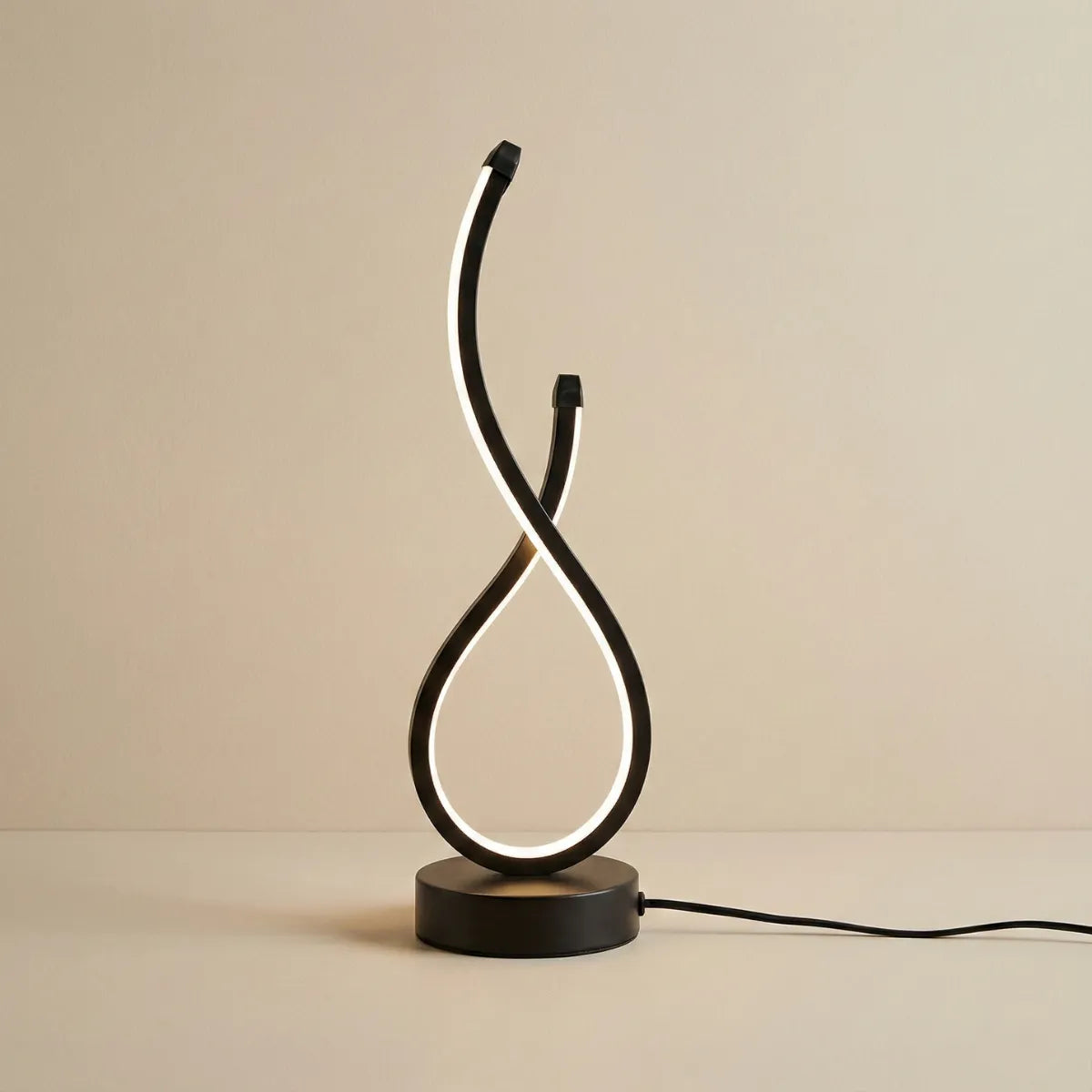 Luminária de mesa Infinity preta, com design moderno em curva de LED (formato de infinito), acesa em luz branca suave, em fundo neutro.