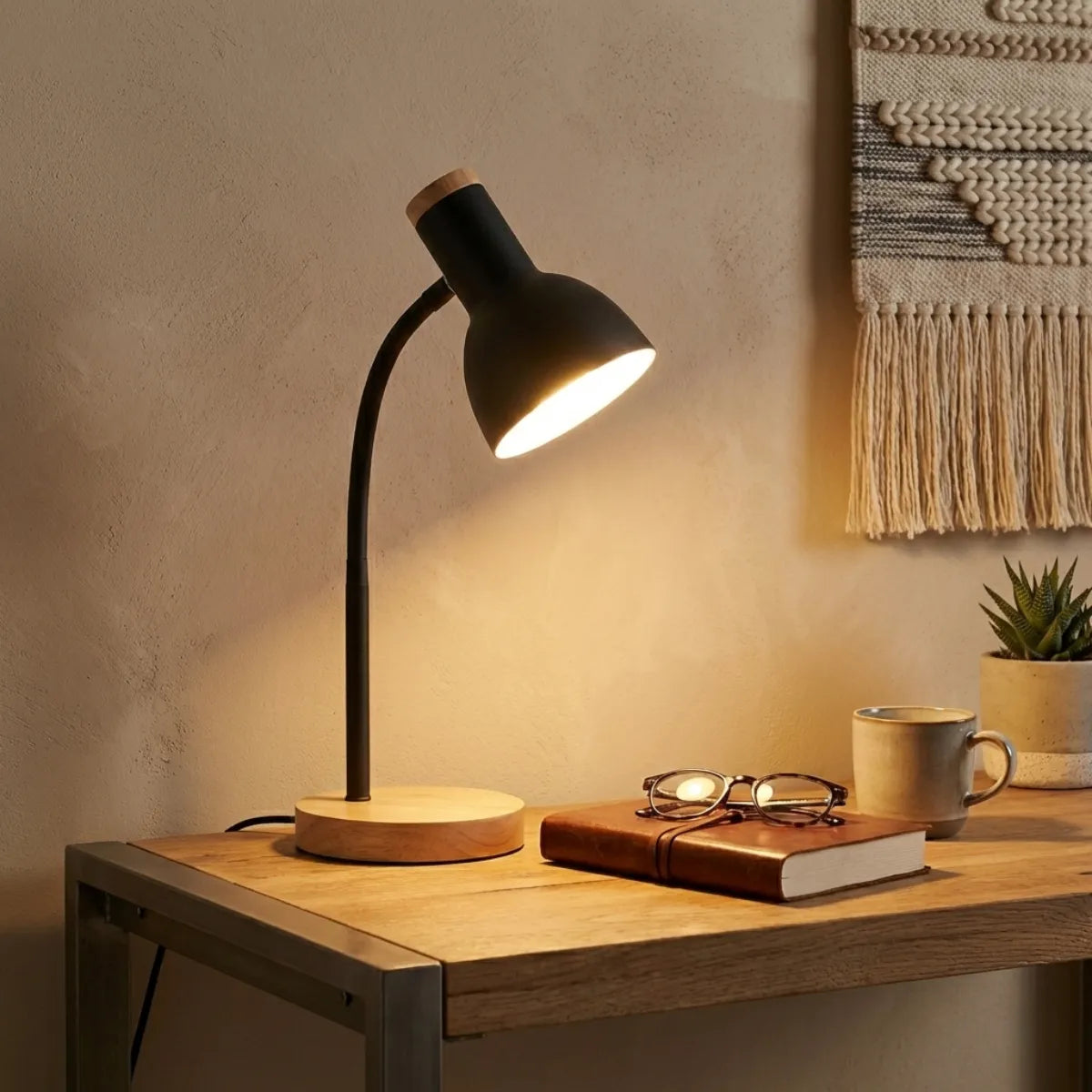 Luminária de mesa para leitura Locus preta iluminando escrivaninha de trabalho com óculos e caderno em home office organizado.