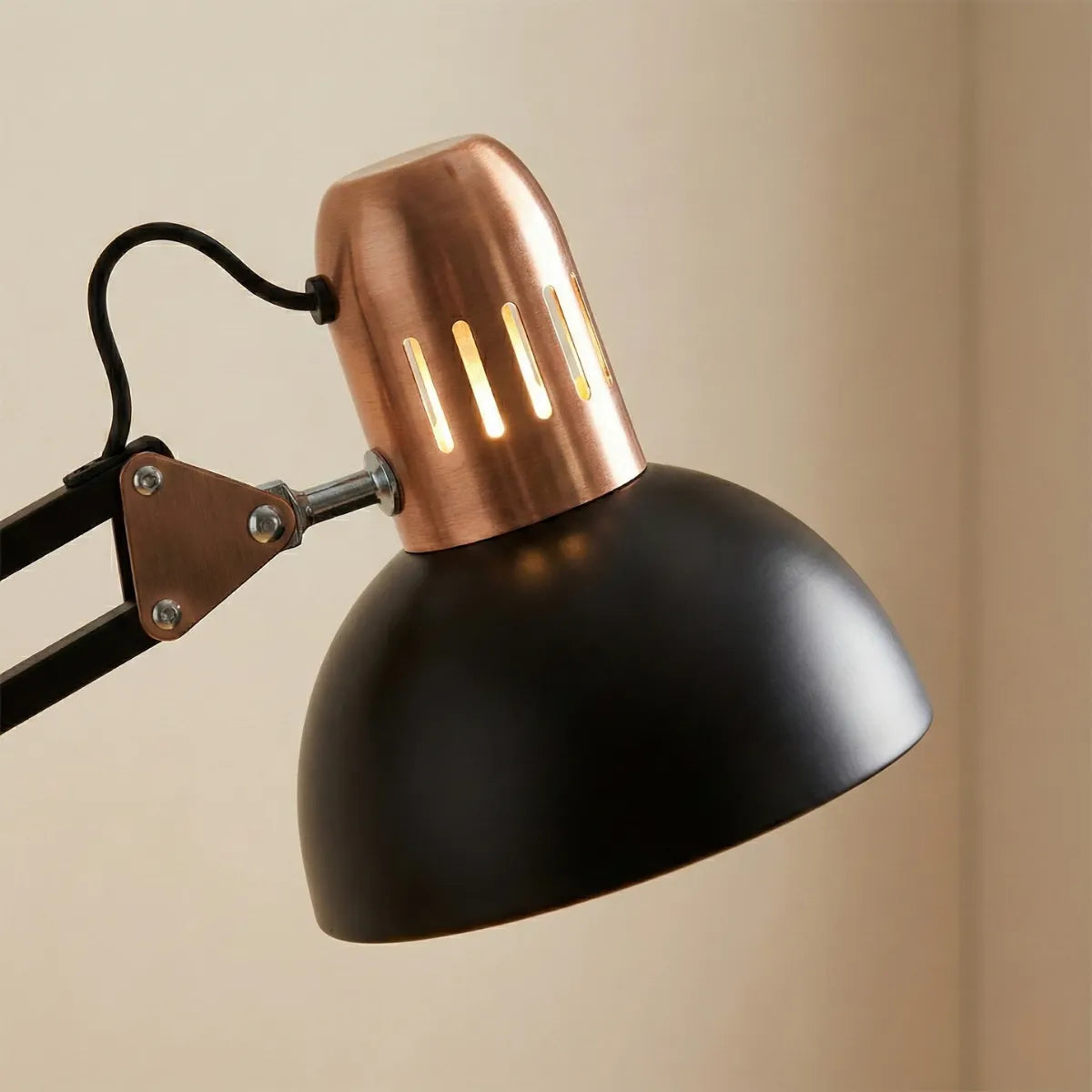 Detalhe da cúpula da luminária preta fosca com acabamento superior em cobre vintage e frestas decorativas, destacando o design industrial retrô.