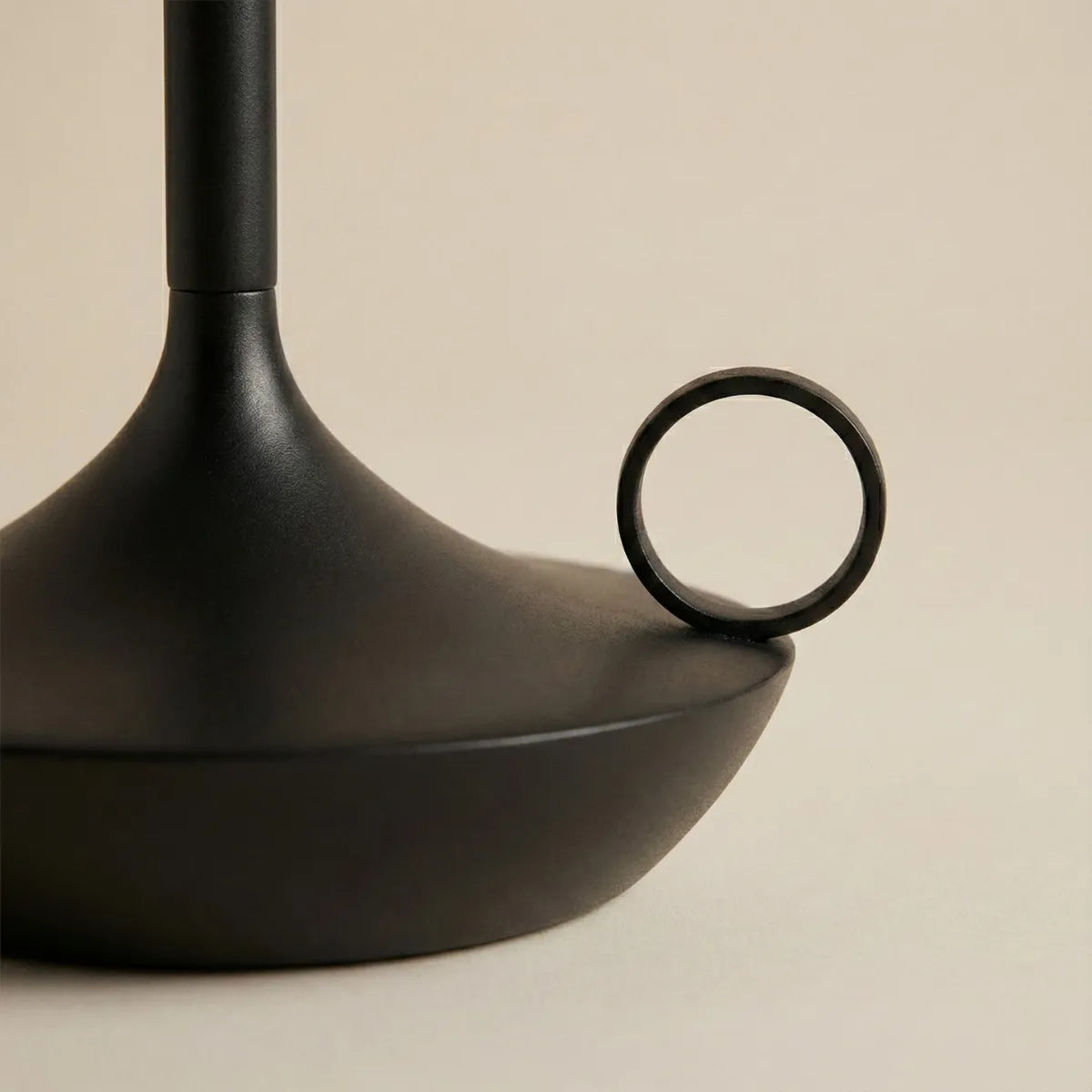 Close-up da base da luminária Venia em preto, destacando a argola de manuseio e o acabamento premium.