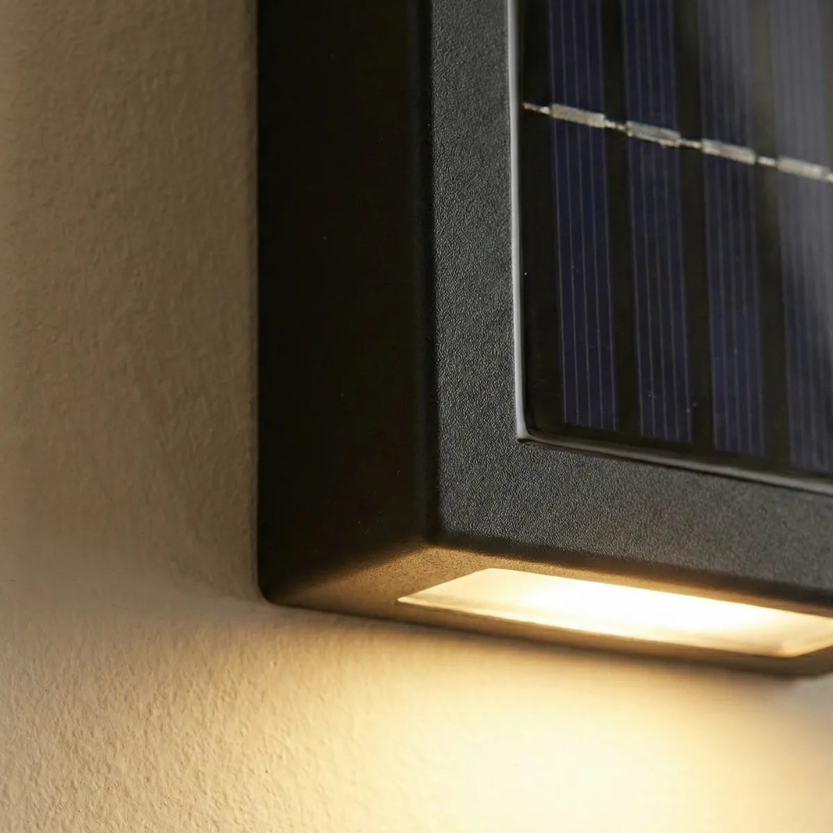 Detalhe em close do painel solar integrado e acabamento preto texturizado da arandela externa com foco na luz LED quente.