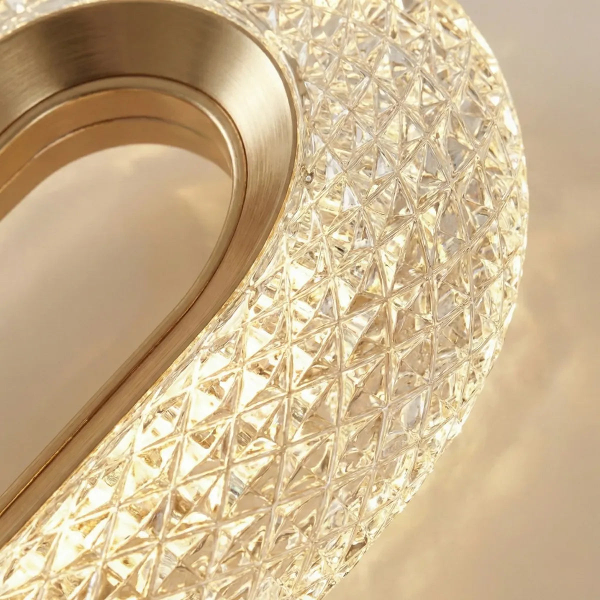 Detalhe da textura facetada do cristal e do acabamento interno em metal dourado da luminária pendente sofisticada.