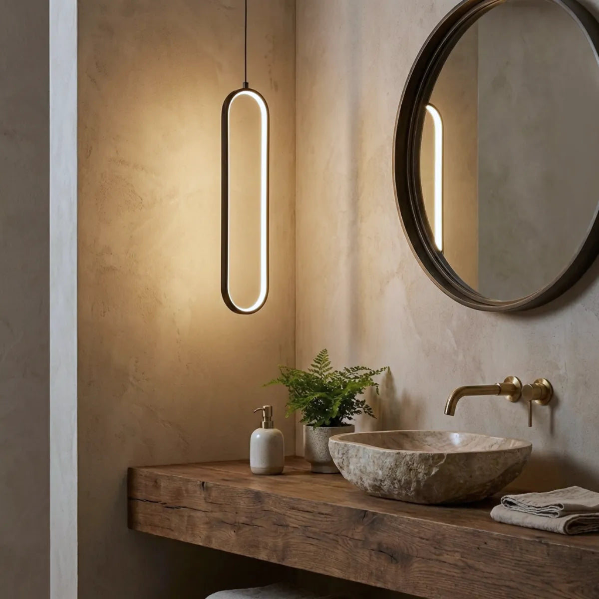 Luminária pendente moderna Elo preta decorando lavabo rústico chique com cuba de pedra natural e espelho redondo.